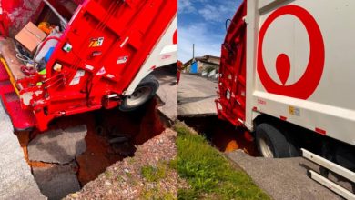 Cratera se abre em rua de Brusque e caminhão de lixo fica preso; trabalhador sofre escoriações